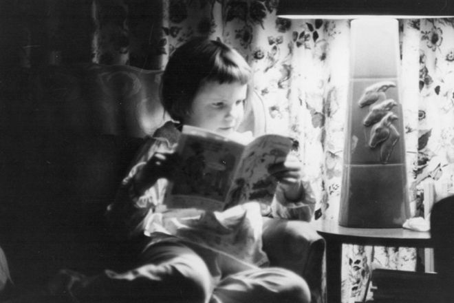 На черно-белой фотографии Кэти читает комикс или другой журнал