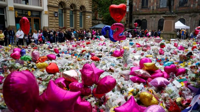 Люди смотрят на цветы и дань, оставленные в Манчестере - через неделю после теракта