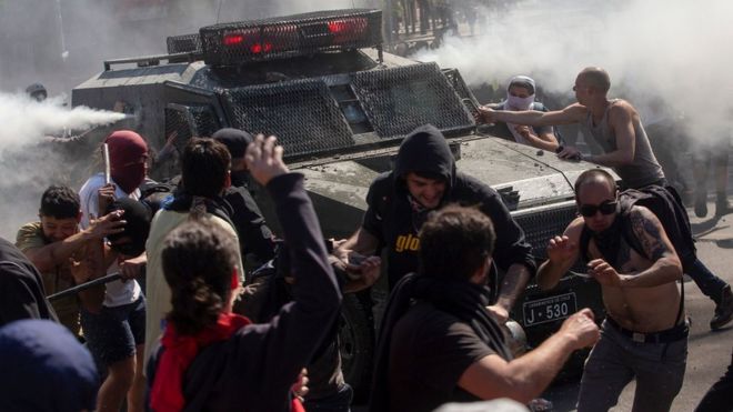 Demonstrators clash with a riot police vehicle during protests in Santiago