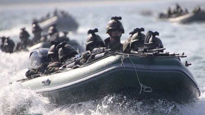 Un bote inflable lleno de soldados y otros detrás