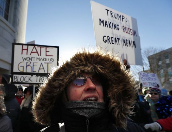 Протестующие против Дональда Трампа выдерживают холодную демонстрацию возле здания Государственного дома в Августе, штат Мэн, в понедельник, 19 декабря 2016 года.