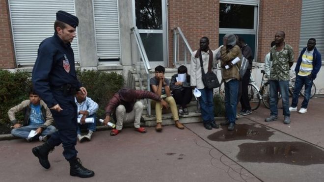 Французский офицер ОМОНа проходит нелегальными мигрантами в Кале 20 августа 2015 года