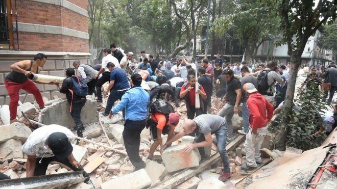 Personas recogiendo escombros de un edificio