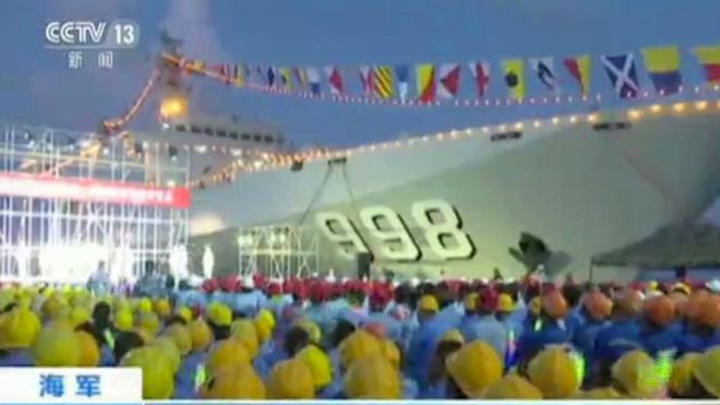 Размытое изображение, снятое на китайских телевизионных кадрах, показывает, что рабочие собираются возле китайского военного корабля во время выступления на Огненном Крестовом рифе в Южно-Китайском море (май 2016 года)