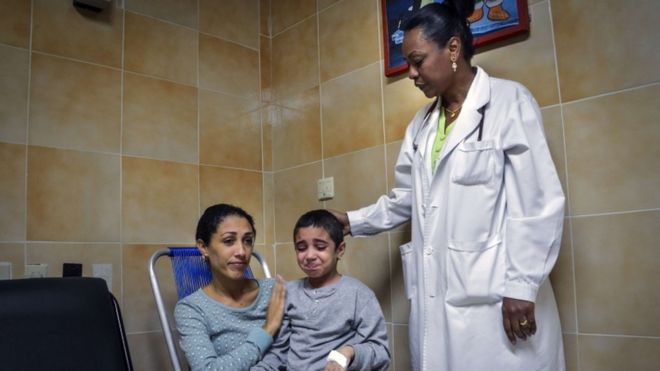 Кубинский доктор наук в области онкологии Мигдалия Перес (справа) стоит рядом с 6-летней больной раком Ноеми Бернардес и ее матерью Элизабет Наварро (слева) в Онкологической больнице Гаваны, 26 октября 2015 года