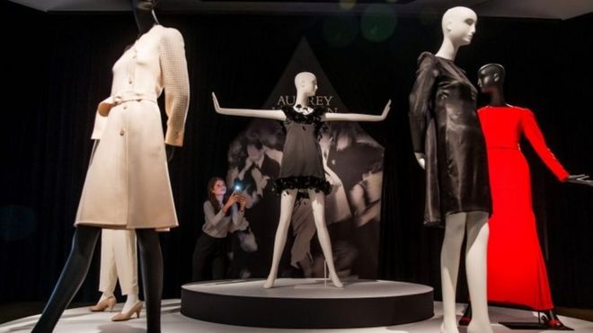 Сотрудник позирует перед черным атласным коктейльным платьем, украшенным перьями от Givenchy Couture, с начальной ценой в ? 50 000 - ? 80 000