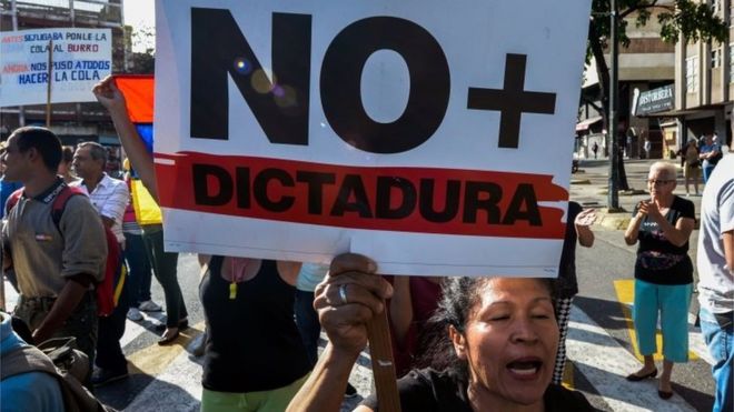 A Venezuelan opposition activist, holds a sign reading "No more dictatorship" and chants slogans against the government of President Nicolas Maduro, during a march along a street of Caracas on March 31, 2017.