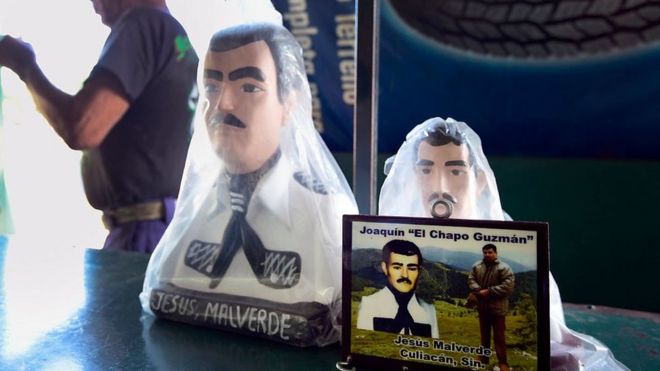 Una foto de Joaquín "el Chapo" Guzmán frente a dos figuras de Malverde en una tienda contigua a una capilla dedicada al santo en Culiacán, Sinaloa, México, el 7 de diciembre de 2016.
