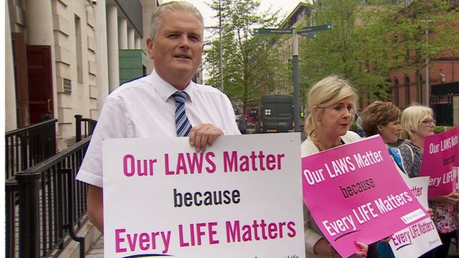 Политик DUP Джим Уэллс и активист кампании за жизнь Берни Смит держат в руках знаки против абортов