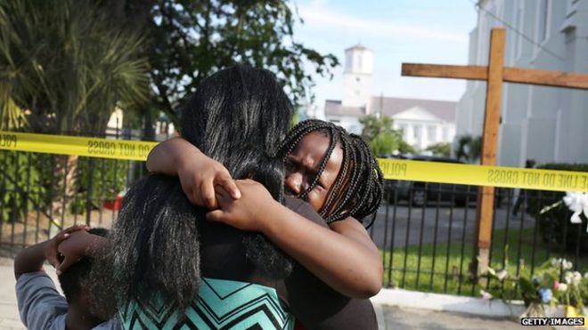 Скорбящие собрались возле Африканской методистской епископальной церкви Эмануэля в Чарльстоне после массовой стрельбы, в результате которой погибли девять человек.