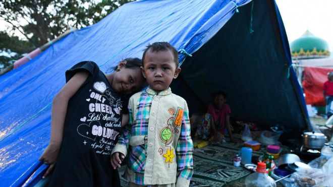 Дети позируют перед палаткой на поле мечети, где они нашли убежище в Палу