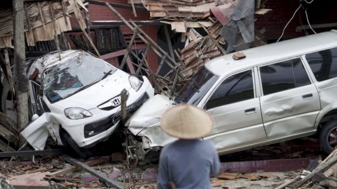 Um homem observa os destroços causados por um tsunami