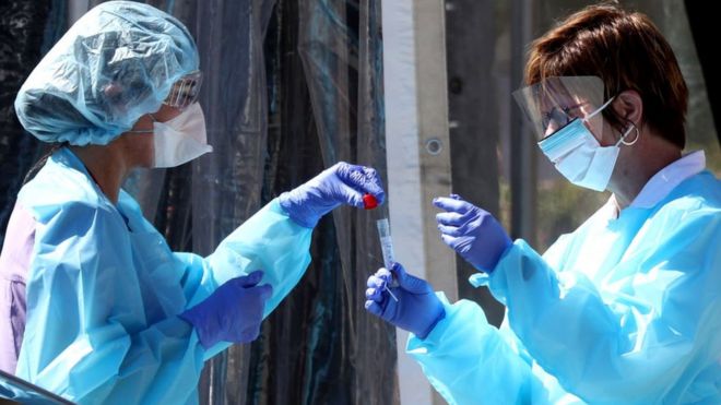 Medical personnel secure a sample from a person at a drive-thru Coronavirus testing station in the US. 12 March 2020