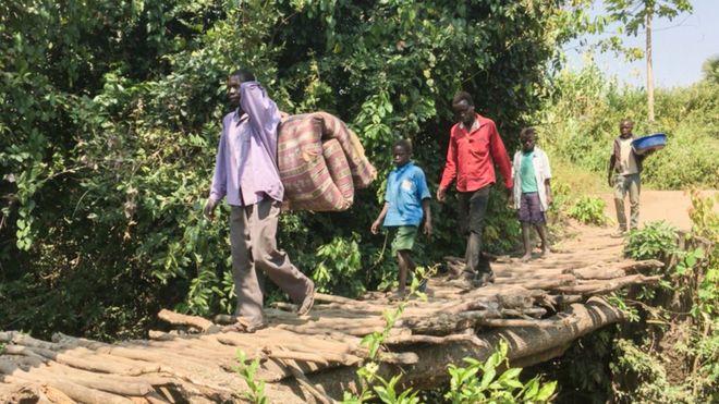 Беженцы пересекают рудиментарный мост, направляясь в Уганду