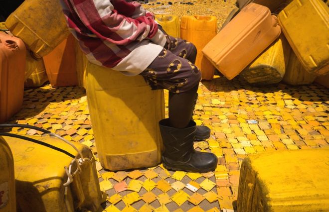 Кто-то сидит на канистре с желтым гобеленом, созданным художником Сержем Аттуквеем Клотти на дороге в Ла - Аккра, Гана