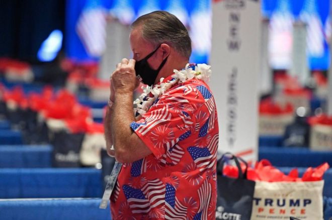 Делегат носит маску и гавайский флаг, покрытый флагами США