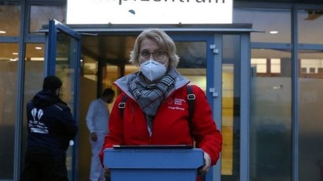 عامل يحمل لقاحات كوفيد 19