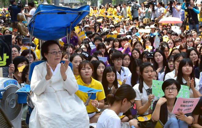Бывшая южнокорейская «женщина для утех» Ли Юн Су (слева), которая была вынуждена служить секс-рабыней для японских войск во время Второй мировой войны, участвует в акции протеста вместе с другими сторонниками, требуя извинений Токио за принуждение женщин к военным борделям во время Второй мировой войны. II у японского посольства в Сеуле 12 августа 2015 года.