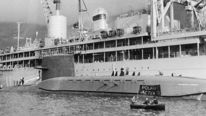 Протестующие CND гребут небольшой корабль вместе с американской подводной лодкой Polaris «USS Patrick Henry» на 6700 тонн на Святом Лохе Шотландии 8 марта 1961 года.