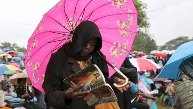 Женщина молится под зонтиком
