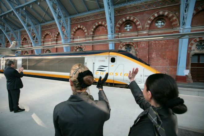 Сотрудники Eurostar машут рукой перед первым высокоскоростным поездом в Париж на новом терминале на станции Сент-Панкрас