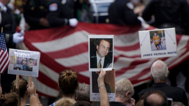Люди держат фотографии жертв во время панихиды в Нью-Йорке, посвященной 9/11.