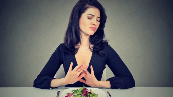 Mujer rechazando un plato de verduras