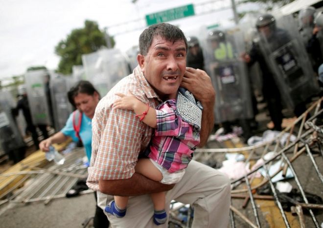 Гондурасец защищает своего ребенка на фоне столкновений между мигрантами и мексиканской полицией