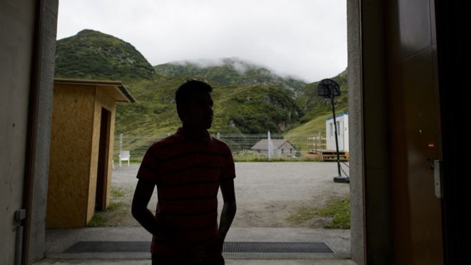 Силуэт лица, ищущего убежища, у входа в военный бункер в отдаленной альпийской деревне Реальп, центральная Швейцария, в 2013 году