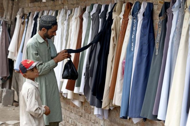 Пакистанский мужчина покупает использованную одежду, готовясь к предстоящему фестивалю Ид аль-Фитр, посвященному окончанию священного постного месяца Рамадан, в Пешаваре, Пакистан, 13 июня 2018 года