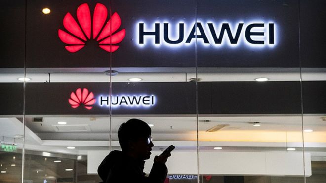 Пешеход разговаривает по телефону, проходя мимо магазина Huawei в Пекине