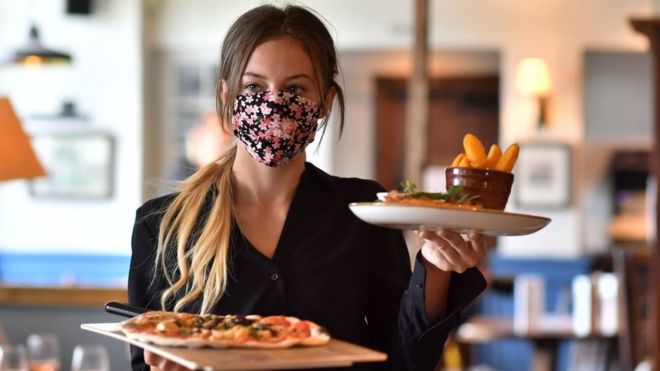 Официантка в маске подает еду