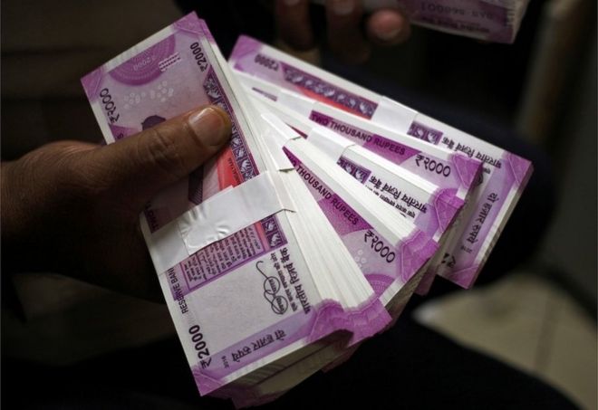 Кассир показывает новые 2000 банкнот индийской рупии в банке в Джамму, 15 ноября 2016 года.