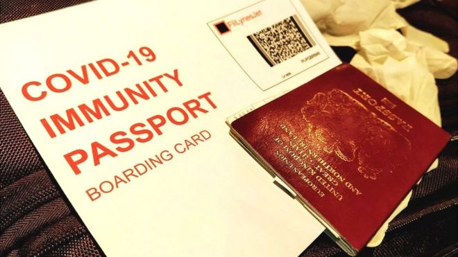 A mock-up of a Covid-19 Immunity passport boarding card, passport and gloves on a suitcase