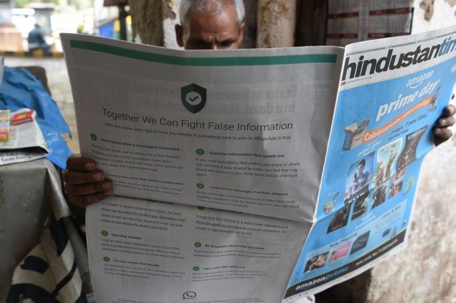 Индийский газетный продавец читает газету с рекламой на последней странице от WhatsApp, предназначенной для противодействия поддельной информации в Дели 10 июля 2018 года.