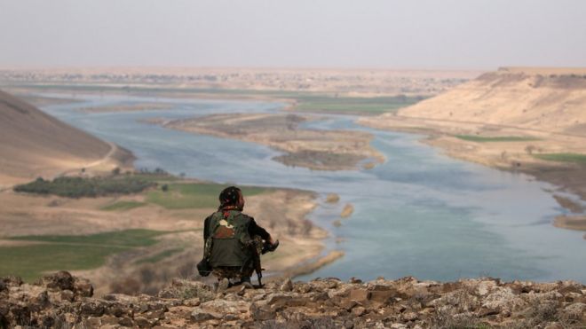 Боец сирийских демократических сил (SDF) отдыхает, глядя на реку Евфрат, к северу от города Ракка, Сирия 8 марта 2017 года