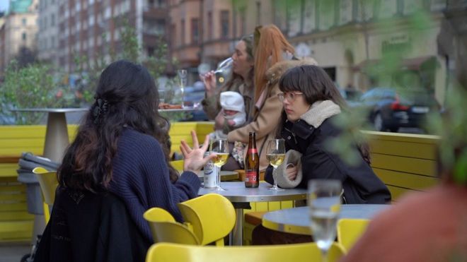 Young women drink and socialise in an outdoor seating area of a bar