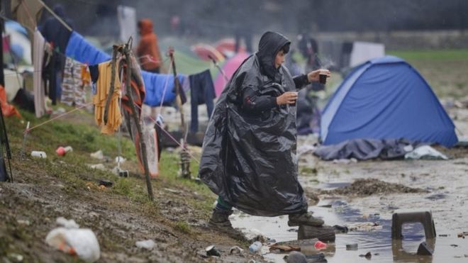 Сумка для мальчика ступает на бревно, чтобы пересечь бассейн с водой в лагере Идомени, северная Греция. Фото: 14 марта 2016 г.