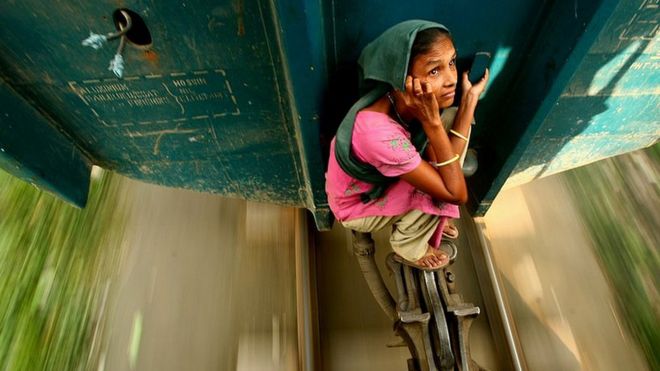 A woman travelling on the locking system of a carriage. Dhaka, Bangladesh