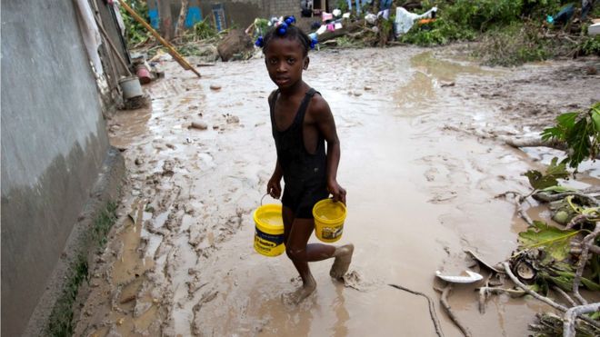 A girl lugs buckets of drinking water after the passing of Hurricane Matthew in Les Cayes, Haiti, 6 October