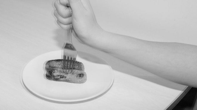 Una persona pinchando unas salchichas con un tenedor