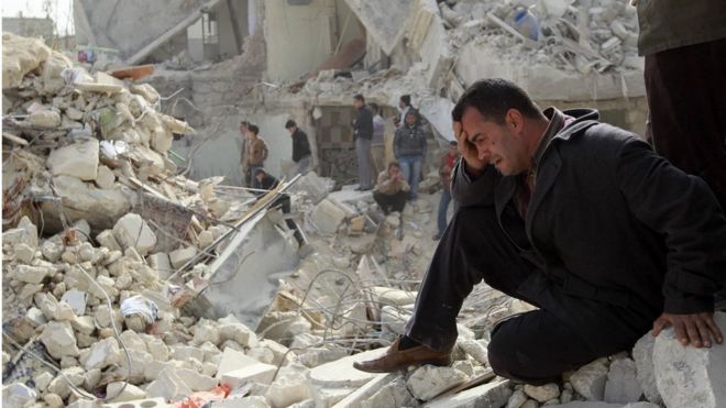 Житель Алеппо на руинах здания