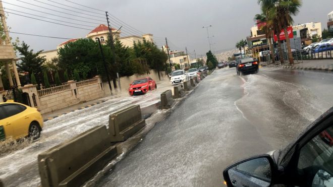 Транспортные средства проезжают через дождевую воду после внезапной грозы на улице Аммана, Иордания, 25 октября 2018 года