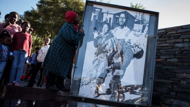 A woman holds the iconic photograph taken by legendary photographer Sam Nzima in 1976