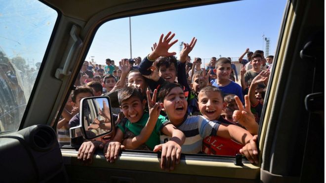 Иракские мальчики собираются на дороге, приветствуя сотрудников иракских сил безопасности, которые продолжают наступать на военных машинах в Киркуке, Ирак, 16 октября 2017 года.