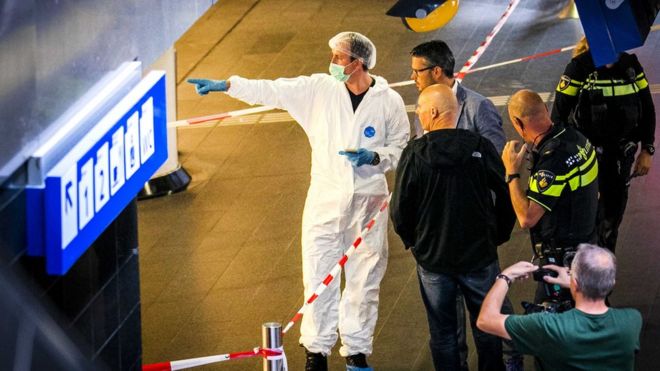 Police investigators stand together near the crime scene at the central train station after a stabbing incident in Amsterdam, Netherlands, 31 August