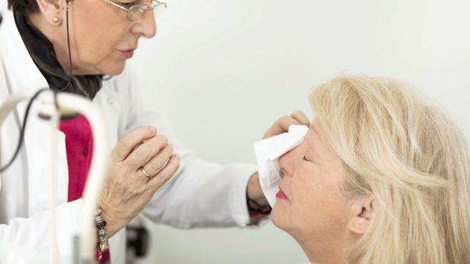 Woman having her eye treated by a doctor