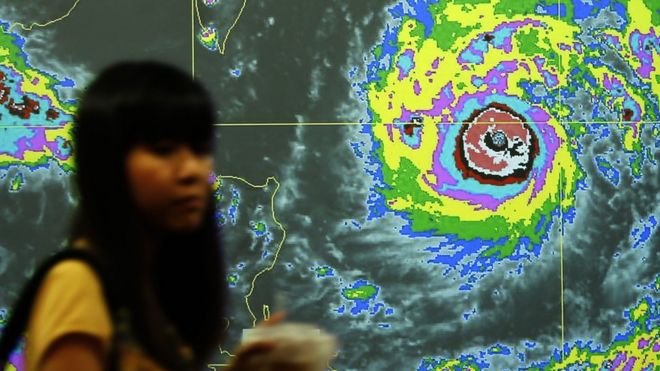 Тайваньец проходит мимо видеоэкрана с графиком Тайфуна Непартак, направляющегося в Тайвань