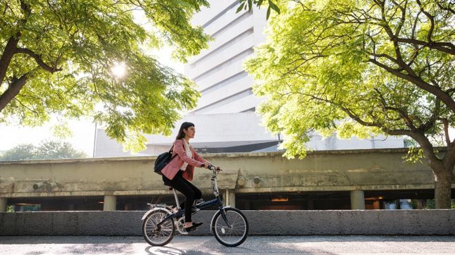 Mujer en bicicleta en una ciudad con árboles
