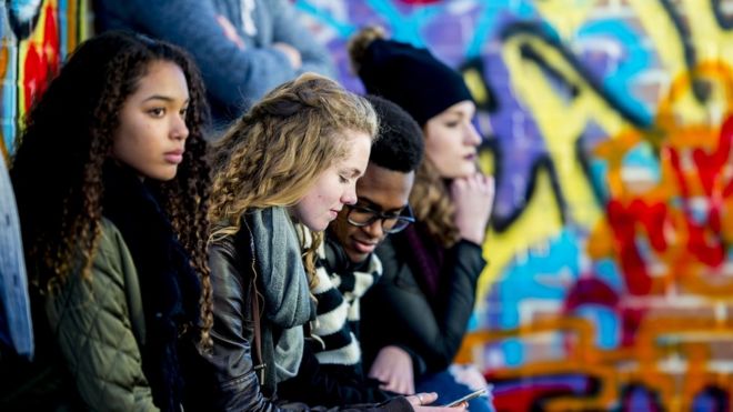 Grupo de jovens em um pátio, observando o entorno e rodeados por grafites